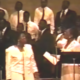 Order My Steps - ORiginal Video with Barbara Tucker standing in front of a choir next to Bettye Nelson on stage, wearing white dresses.